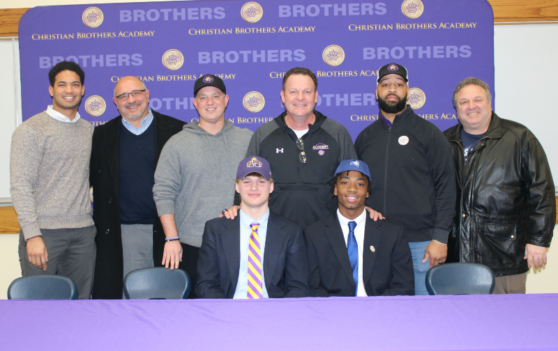 Football Student-Athletes Rae & Pitts Sign Their Division I Letters Of Intent image of coaches with students