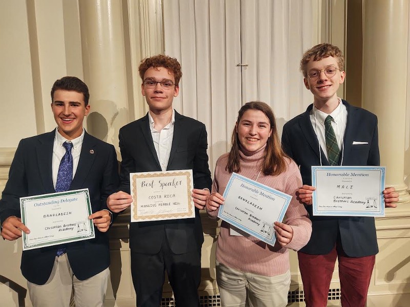 Model UN Team Has Successful Outing At Syracuse University Conference image of four students with awards