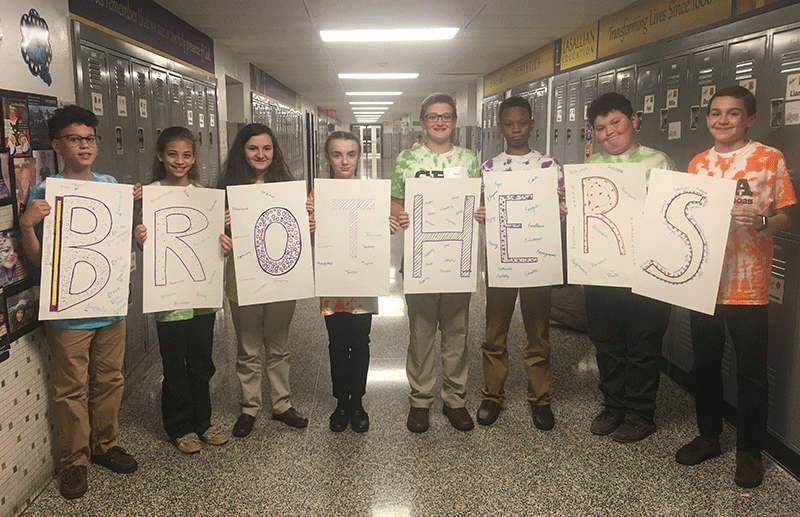 7th grade students holding signs that spell out brothers