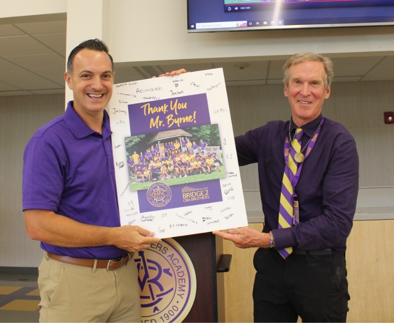 President Matt Keough presents Dan Byrne' 71, who funded the B2B Program with a signed card from the student participants. 