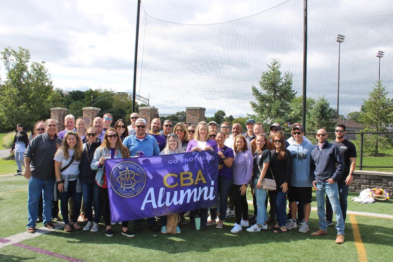 Alumni Association Hosts Homecoming Tailgate near syracuse ny image of alumni holding cba banner