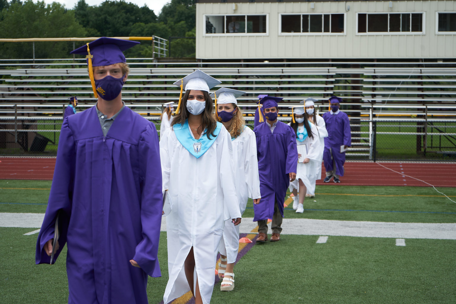 2020 cba graduation image of graduates walking in caps and gowns and masks