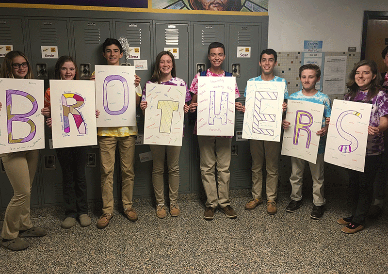 8th grade students holding signs that spell out brothers